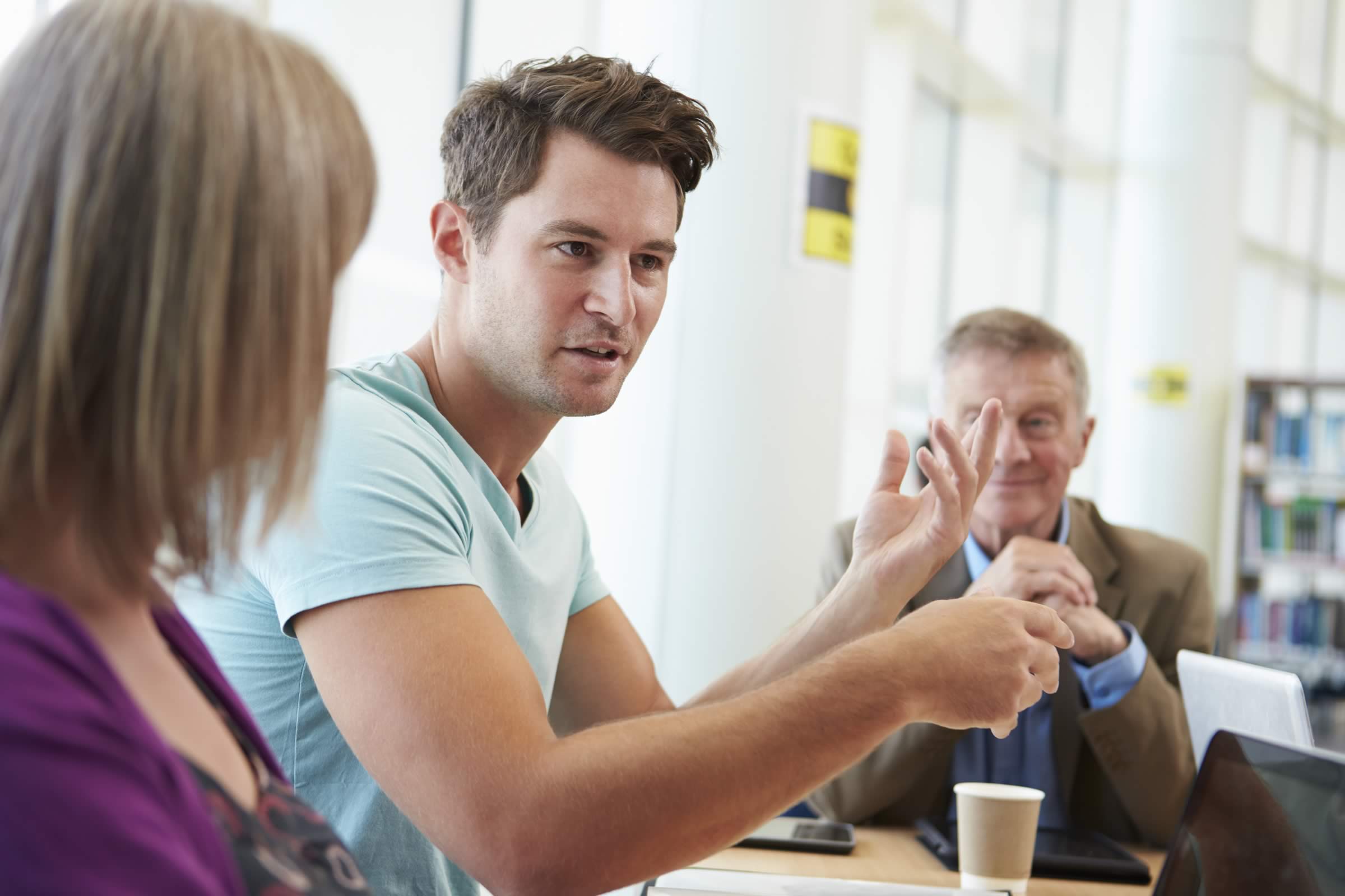 Three people sitting at a table having a discussion.